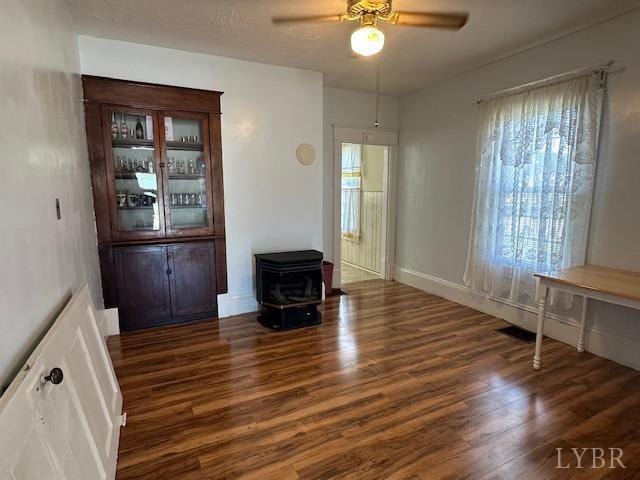 2107 SE Kenwood Blvd, Roanoke, VA 24013 - unfurnished living room featuring a wood stove, wood finished floors, a ceiling fan, and baseboards