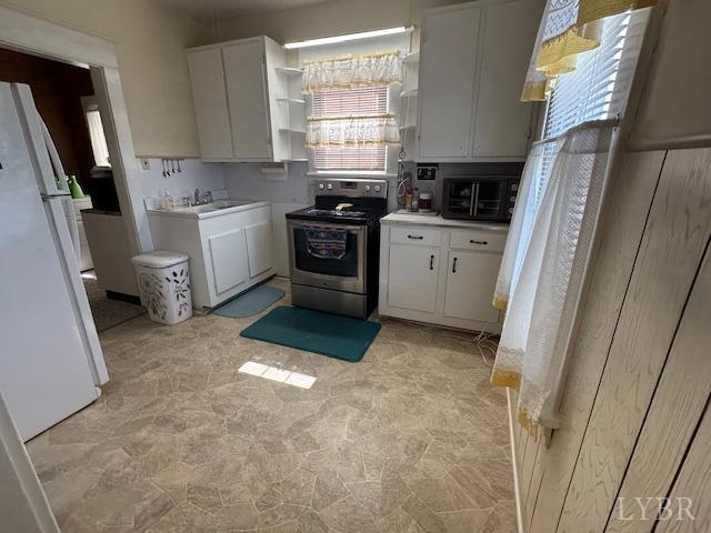 2107 SE Kenwood Blvd, Roanoke, VA 24013 - kitchen featuring stainless steel range with electric stovetop, freestanding refrigerator, white cabinetry, and light countertops