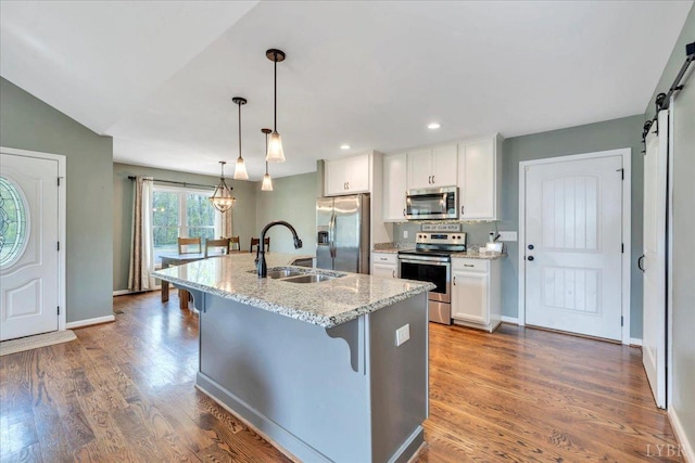 1400 Mountain Cut Rd, Appomattox, VA 24522 - kitchen with a barn door, a breakfast bar, a sink, white cabinets, and appliances with stainless steel finishes