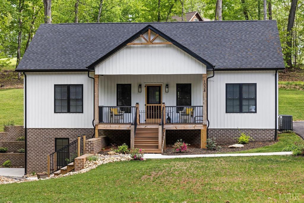 modern farmhouse style home featuring a porch, a front yard, central air condition unit, a shingled roof, and stairs