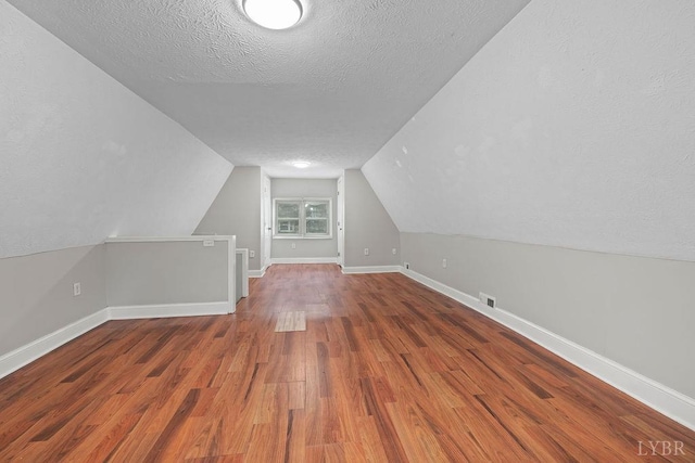 609 Jackson St, Lynchburg, VA 24504 - bonus room featuring a textured ceiling, wood finished floors, vaulted ceiling, and baseboards