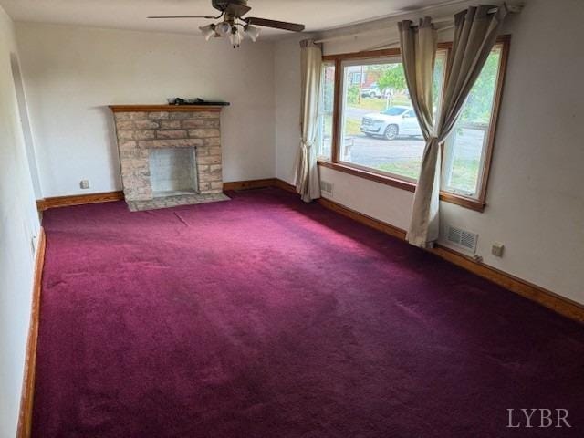 unfurnished living room featuring carpet floors, visible vents, a fireplace, baseboards, and ceiling fan