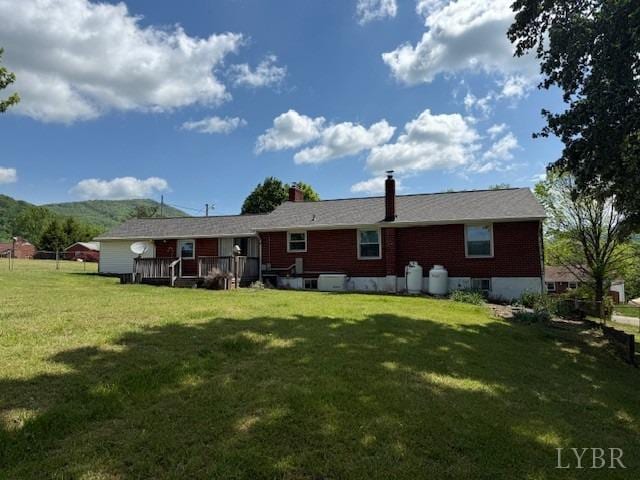 rear view of property featuring a lawn, a deck, and a chimney