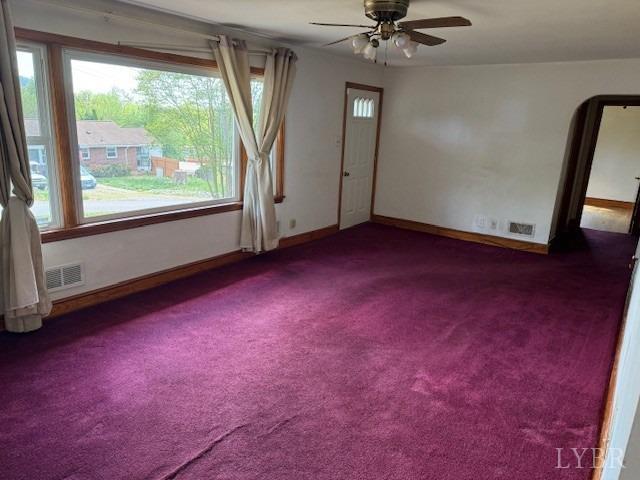 spare room featuring plenty of natural light, carpet flooring, a ceiling fan, and visible vents