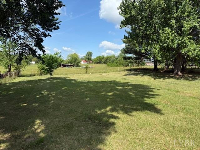 view of yard with fence and a rural view