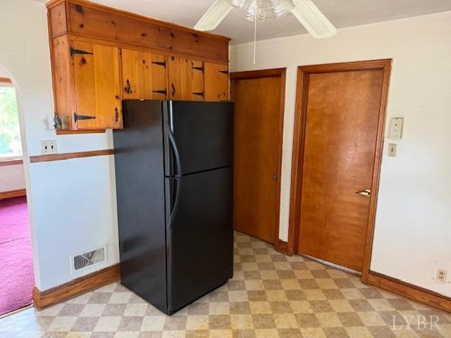 kitchen with freestanding refrigerator, visible vents, brown cabinetry, and light floors