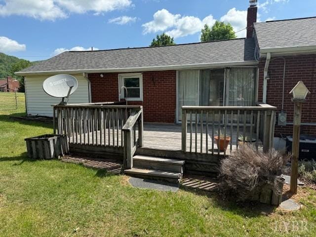 back of property featuring a lawn, a chimney, a deck, and brick siding