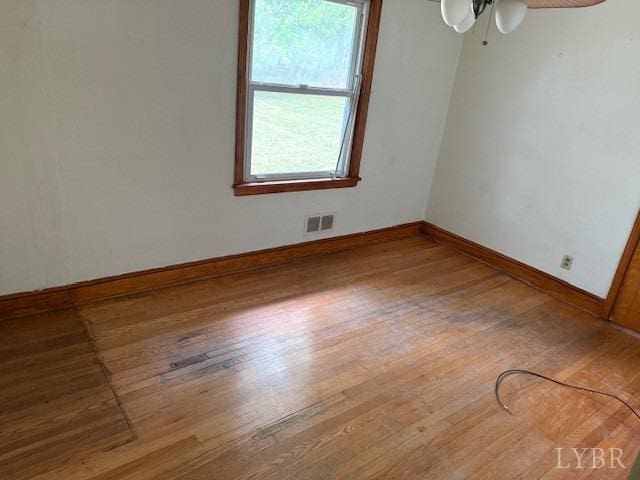 unfurnished room featuring baseboards, a ceiling fan, wood finished floors, and visible vents