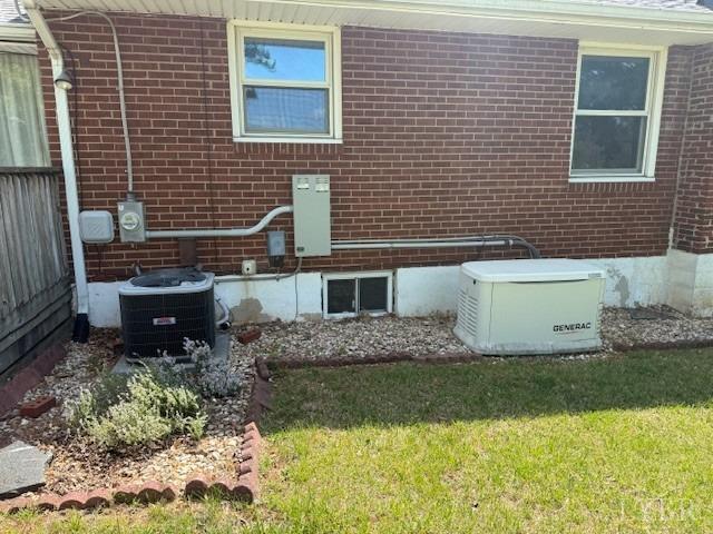 details featuring electric meter, central AC unit, a power unit, and brick siding