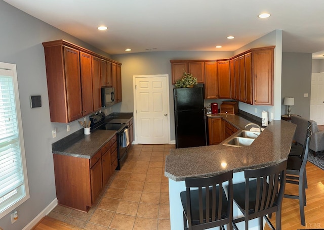 1057 Barrow Hills Dr, Moneta, VA 24104 - kitchen featuring black appliances, a sink, a breakfast bar, a peninsula, and brown cabinetry