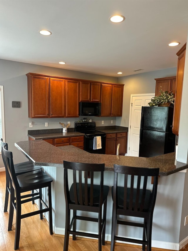 1057 Barrow Hills Dr, Moneta, VA 24104 - kitchen with black appliances, dark countertops, recessed lighting, light wood-style floors, and a breakfast bar area