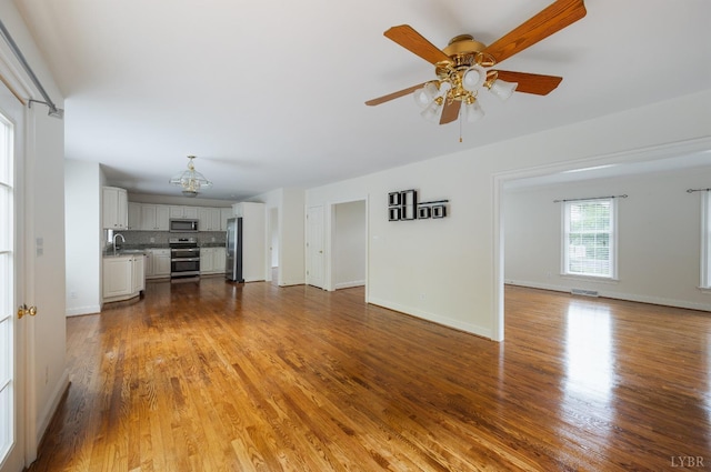 528 Lady Slipper Ln, Lynchburg, VA 24502 - unfurnished living room featuring wood finished floors, a ceiling fan, and a chandelier