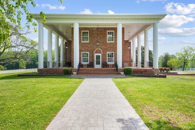 view of front of house with brick siding, a front lawn, and covered porch