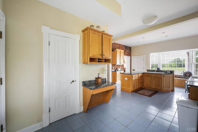kitchen featuring baseboards, dark countertops, a sink, and tile patterned flooring