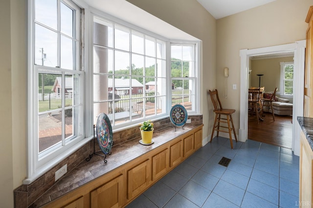 living area with baseboards, visible vents, a healthy amount of sunlight, and tile patterned flooring