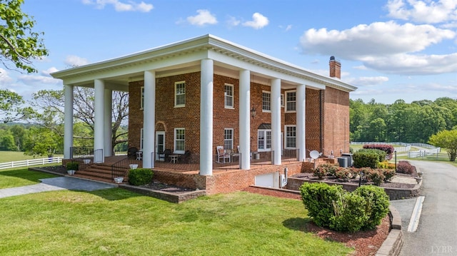 view of home's exterior featuring a yard, brick siding, fence, and a chimney