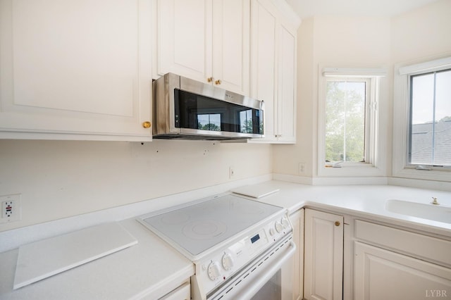 1348 Lake Shore Dr, Forest, VA 24551 - kitchen featuring electric stove, stainless steel microwave, a sink, light countertops, and white cabinetry