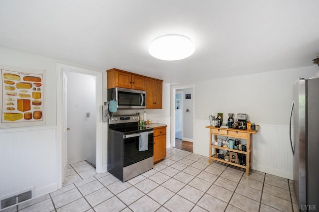 906 Elon Rd, Madison Heights, VA 24572 - kitchen with appliances with stainless steel finishes, light tile patterned floors, wainscoting, brown cabinetry, and light countertops