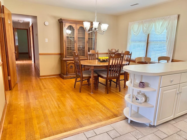 dining room with a chandelier, visible vents, and light wood-style flooring