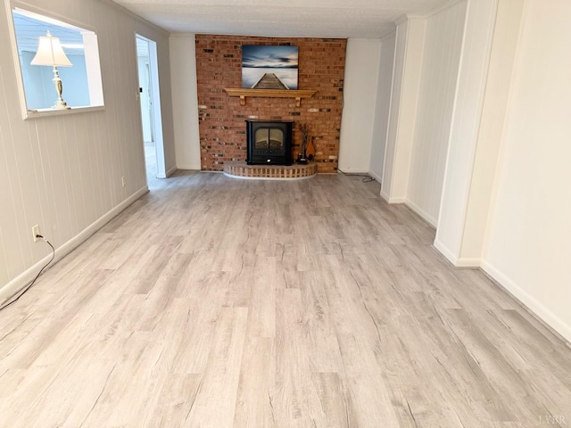 unfurnished living room featuring a fireplace, baseboards, and wood finished floors