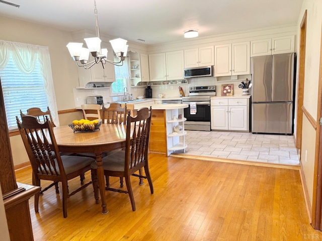 kitchen featuring stainless steel appliances, open shelves, light wood finished floors, light countertops, and a notable chandelier