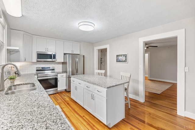 507 Henry St, Gretna, VA 24557 - kitchen with appliances with stainless steel finishes, tasteful backsplash, a sink, white cabinets, and light wood-type flooring