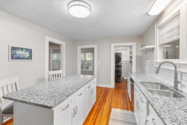 507 Henry St, Gretna, VA 24557 - kitchen featuring a center island, light wood finished floors, a sink, white cabinetry, and stacked washer and clothes dryer