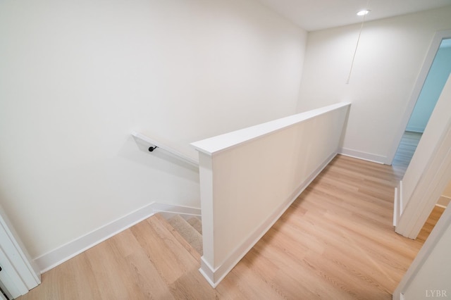 corridor with light wood-style floors, an upstairs landing, baseboards, and recessed lighting