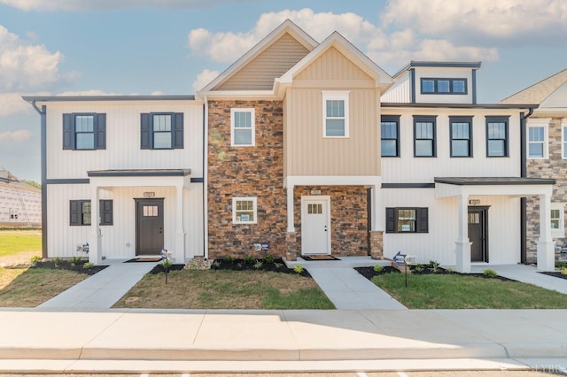 townhome / multi-family property with stone siding and a front lawn