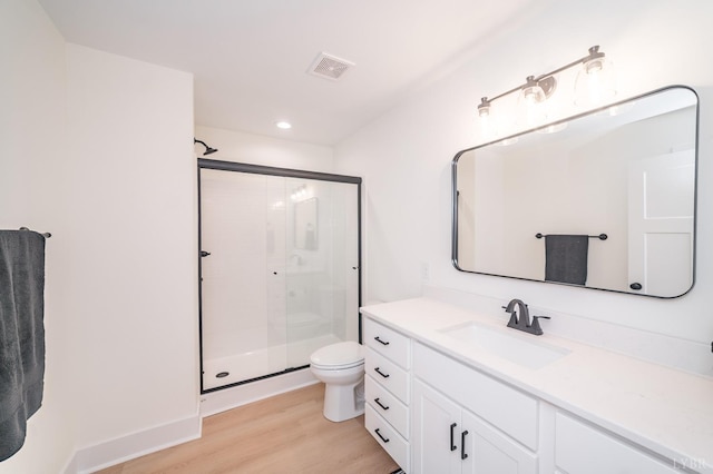 bathroom featuring a stall shower, toilet, visible vents, vanity, and wood finished floors
