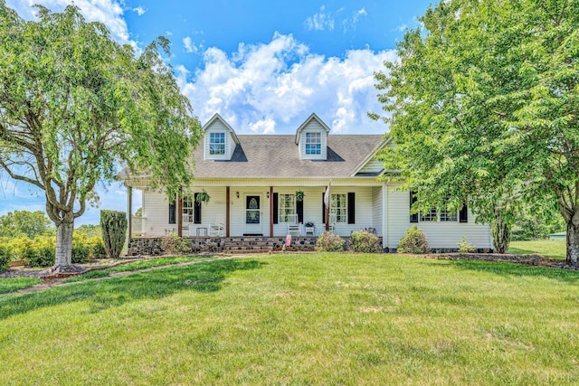 new england style home featuring covered porch, roof with shingles, and a front yard