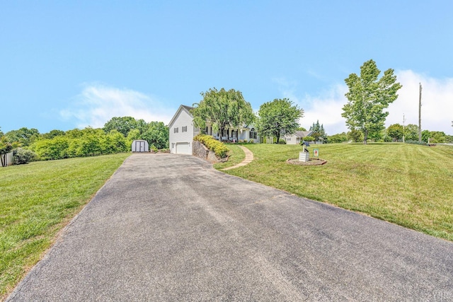 view of front of house with an attached garage, a storage unit, aphalt driveway, a front lawn, and an outdoor structure