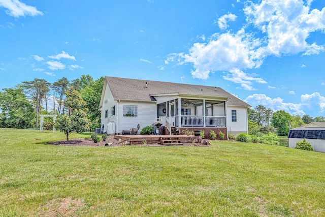 rear view of property featuring a lawn, a wooden deck, a sunroom, and ceiling fan