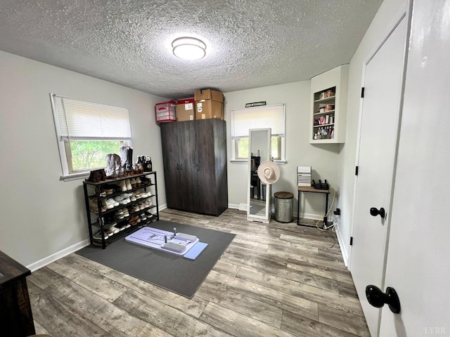 interior space with a textured ceiling, wood finished floors, and baseboards