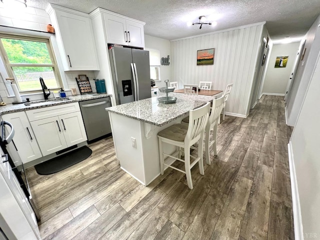 139 Abbitts Dr, Madison Heights, VA 24572 - kitchen with stainless steel appliances, a sink, wood finished floors, white cabinets, and a center island