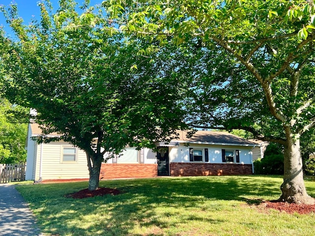 view of front of property with a front yard, brick siding, and fence