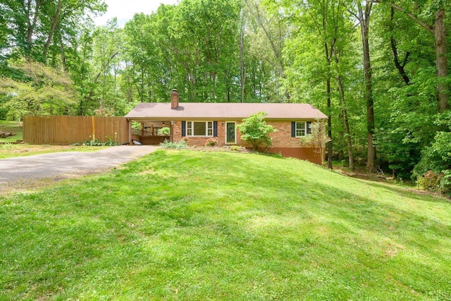 ranch-style home with a chimney, fence, an attached carport, aphalt driveway, and a front lawn