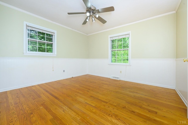 unfurnished room featuring crown molding, a ceiling fan, visible vents, and wood finished floors
