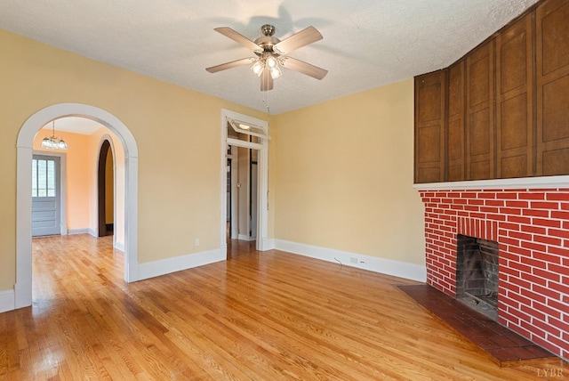 600 9th St, Altavista, VA 24517 - unfurnished living room featuring a fireplace, light wood finished floors, arched walkways, a ceiling fan, and baseboards