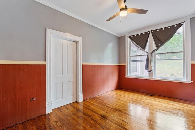 600 9th St, Altavista, VA 24517 - empty room with ornamental molding, visible vents, ceiling fan, a wainscoted wall, and wood finished floors