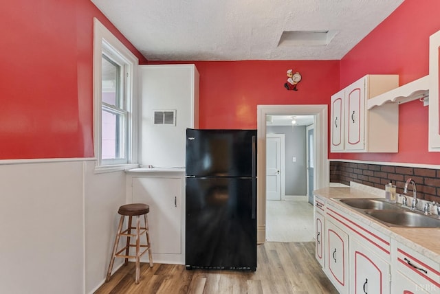 600 9th St, Altavista, VA 24517 - kitchen with freestanding refrigerator, a textured ceiling, light wood finished floors, visible vents, and a sink