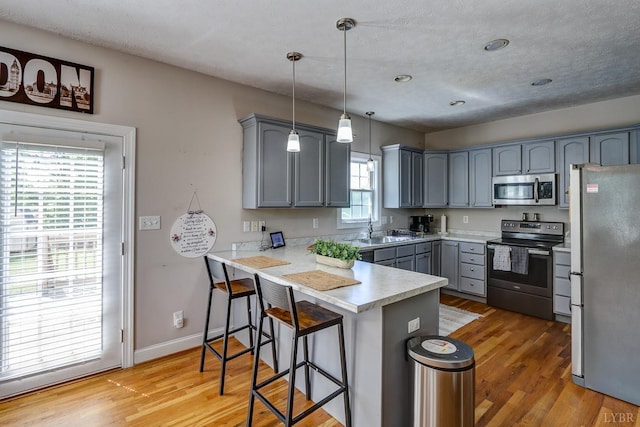 22 Semmes Ct, Rustburg, VA 24588 - kitchen with stainless steel appliances, a peninsula, gray cabinets, a breakfast bar, and light wood finished floors