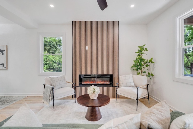 living area featuring healthy amount of natural light, a glass covered fireplace, recessed lighting, wood finished floors, and baseboards