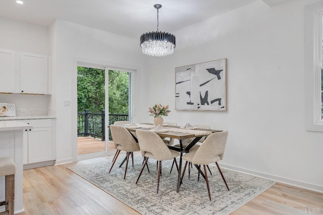 dining space featuring light wood finished floors, a chandelier, and baseboards