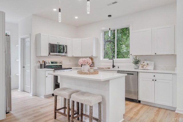 kitchen with appliances with stainless steel finishes, a sink, light wood-style floors, a kitchen breakfast bar, and recessed lighting