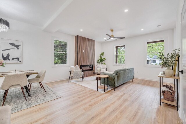living room featuring light wood-type flooring, baseboards, recessed lighting, ceiling fan, and a large fireplace
