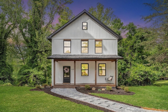 modern farmhouse featuring a porch, a front yard, and roof with shingles