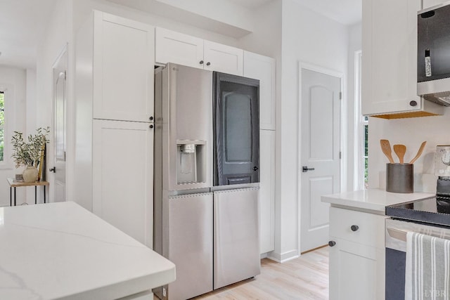 kitchen featuring stainless steel appliances, white cabinetry, light countertops, and light wood-style floors