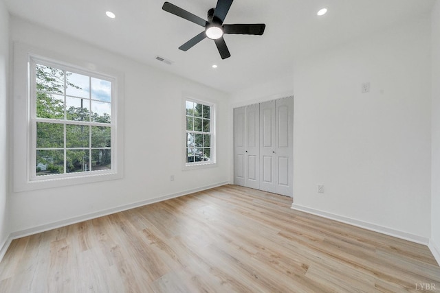 unfurnished bedroom with multiple windows, light wood-style flooring, baseboards, and recessed lighting