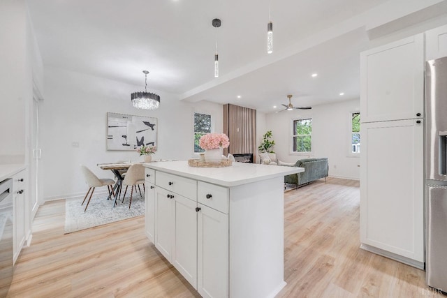 kitchen featuring light wood-style flooring, white cabinets, pendant lighting, a center island, and light countertops